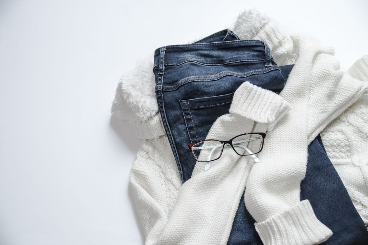 White cable-knit sweater folded with jeans, from the illustrative product example