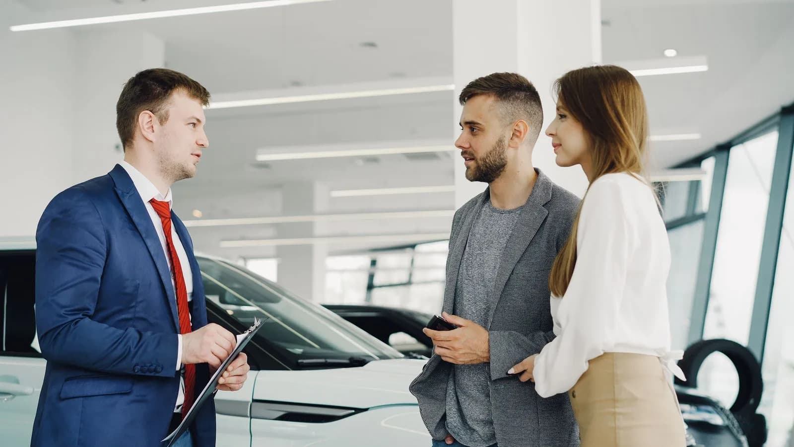 A salesperson talking with customers beside a car in a showroom
