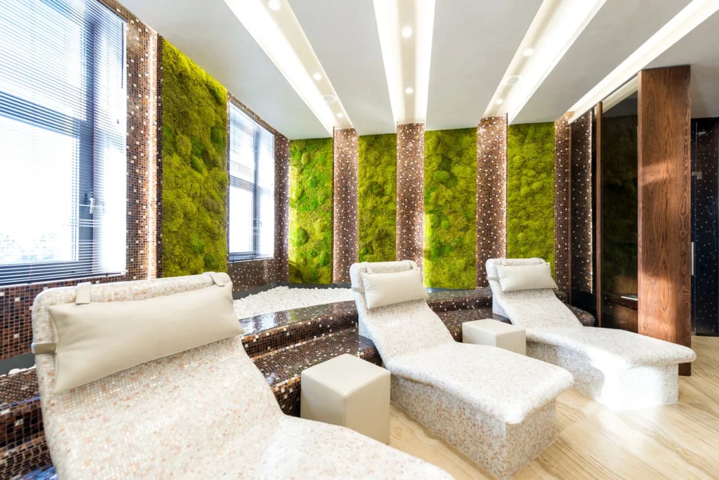 A spa lounge with daybeds and a green moss wall
