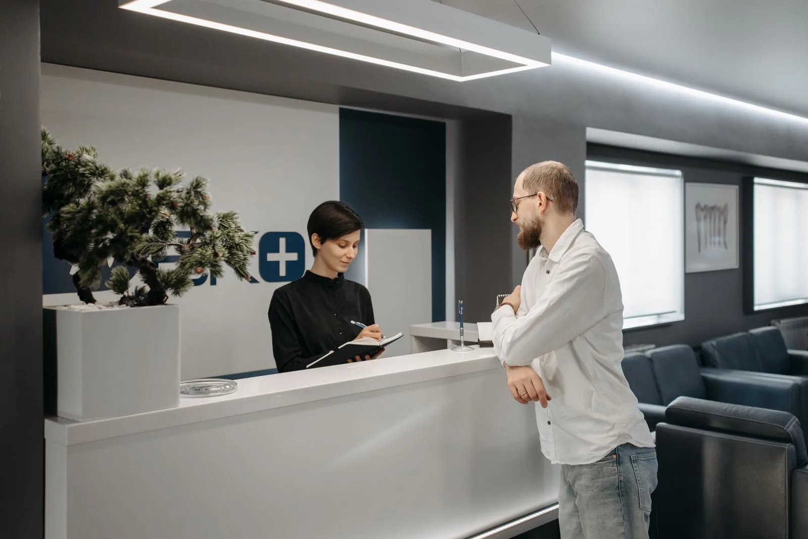 A patient speaking with a receptionist at a modern dental front desk