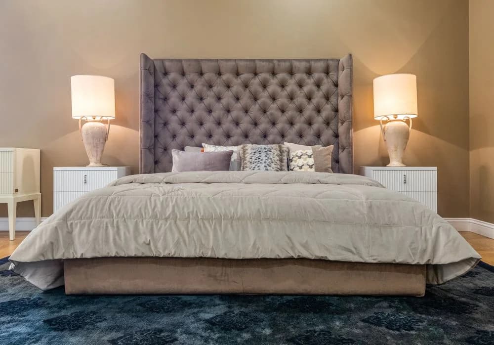 A warmly lit hotel bedroom with a king bed and upholstered headboard