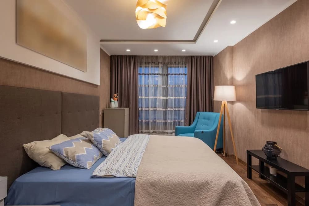 A spacious hotel bedroom with a king bed and a separate seating area