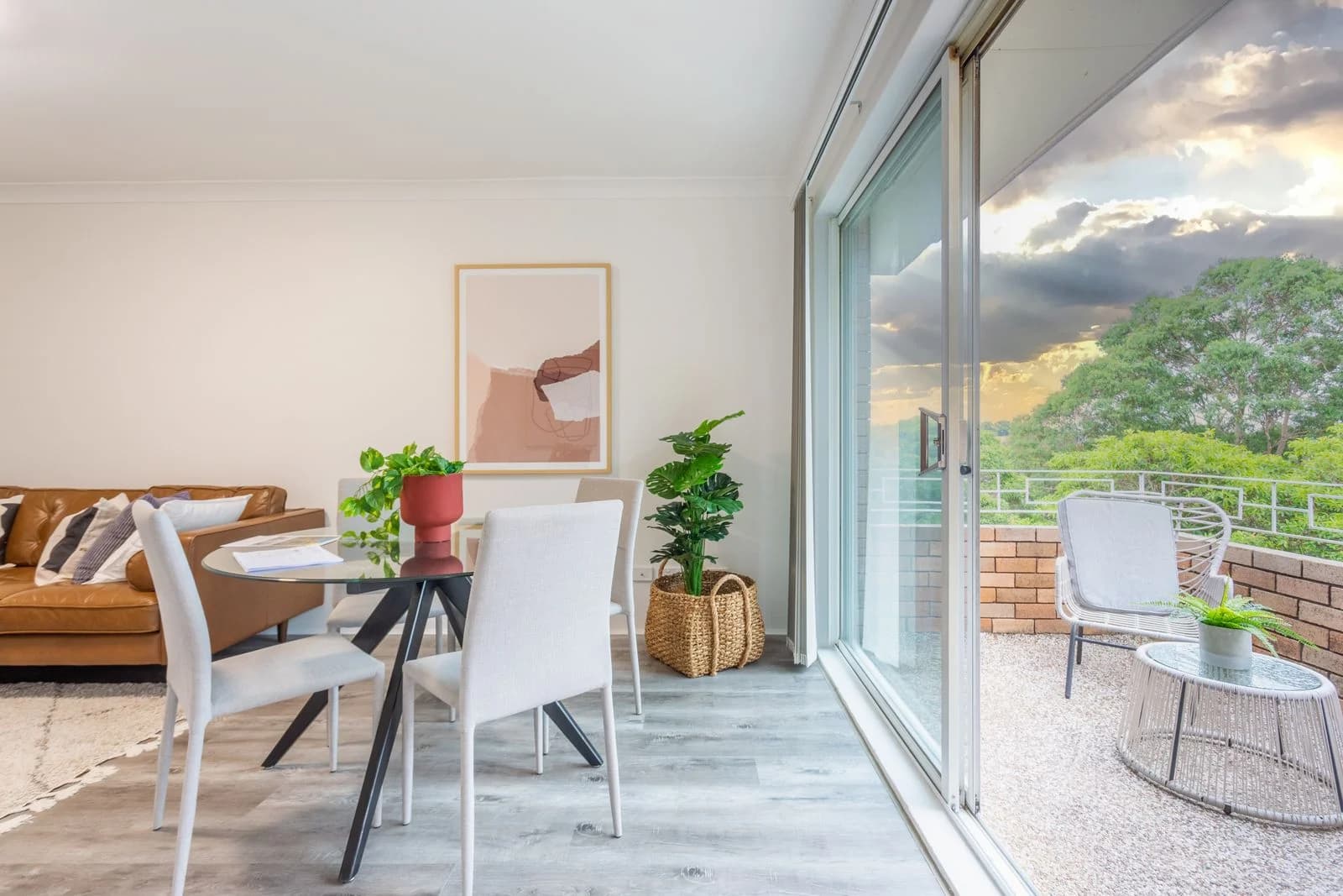 A bright apartment living and dining area opening onto a leafy terrace