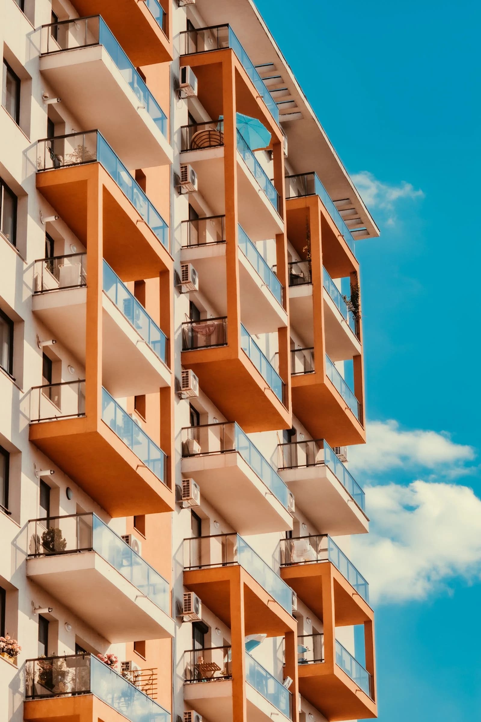 Sunlit apartment balconies with warm terracotta facades and glass railings