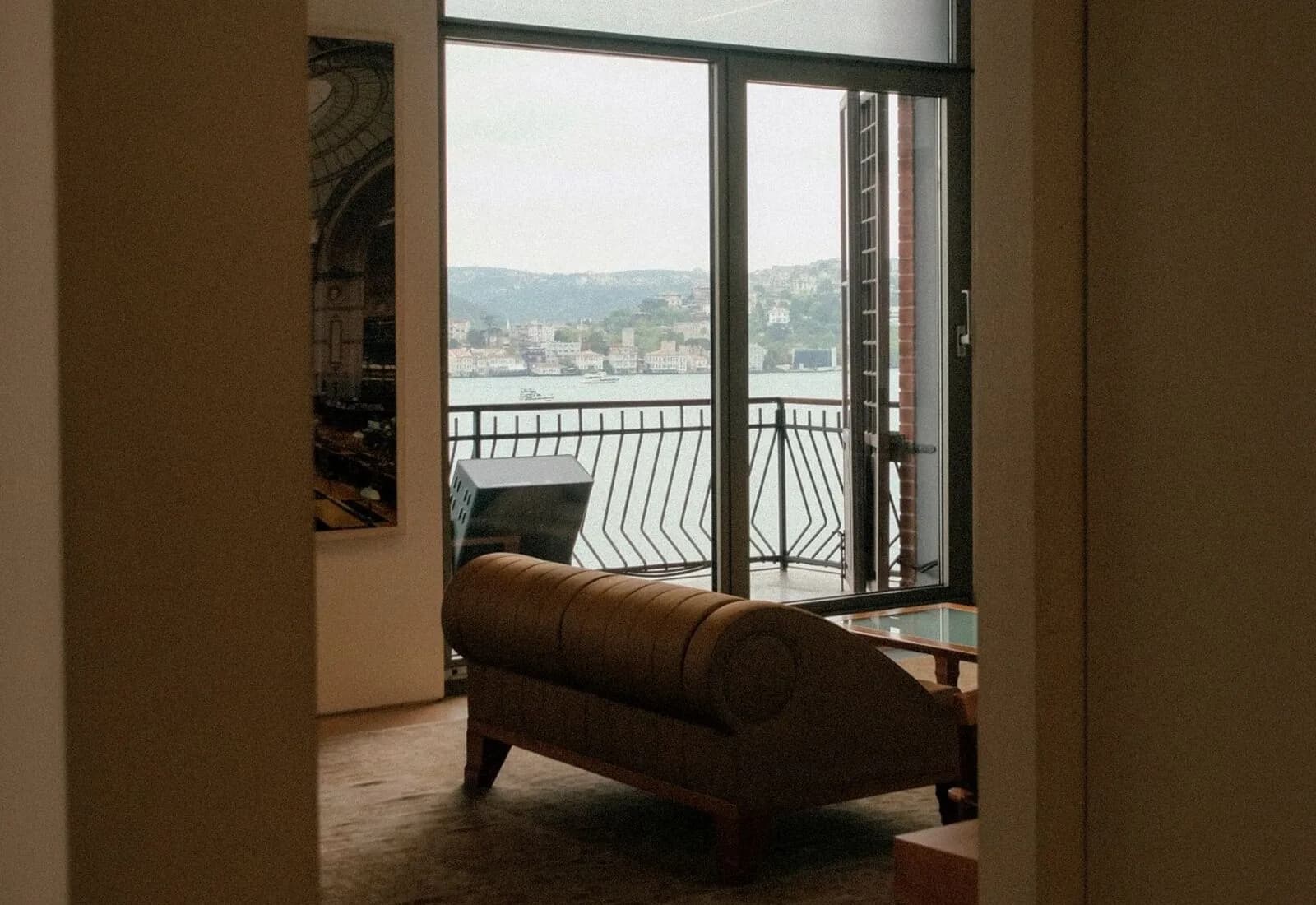 An apartment living room with doors opening to a balcony and a water view
