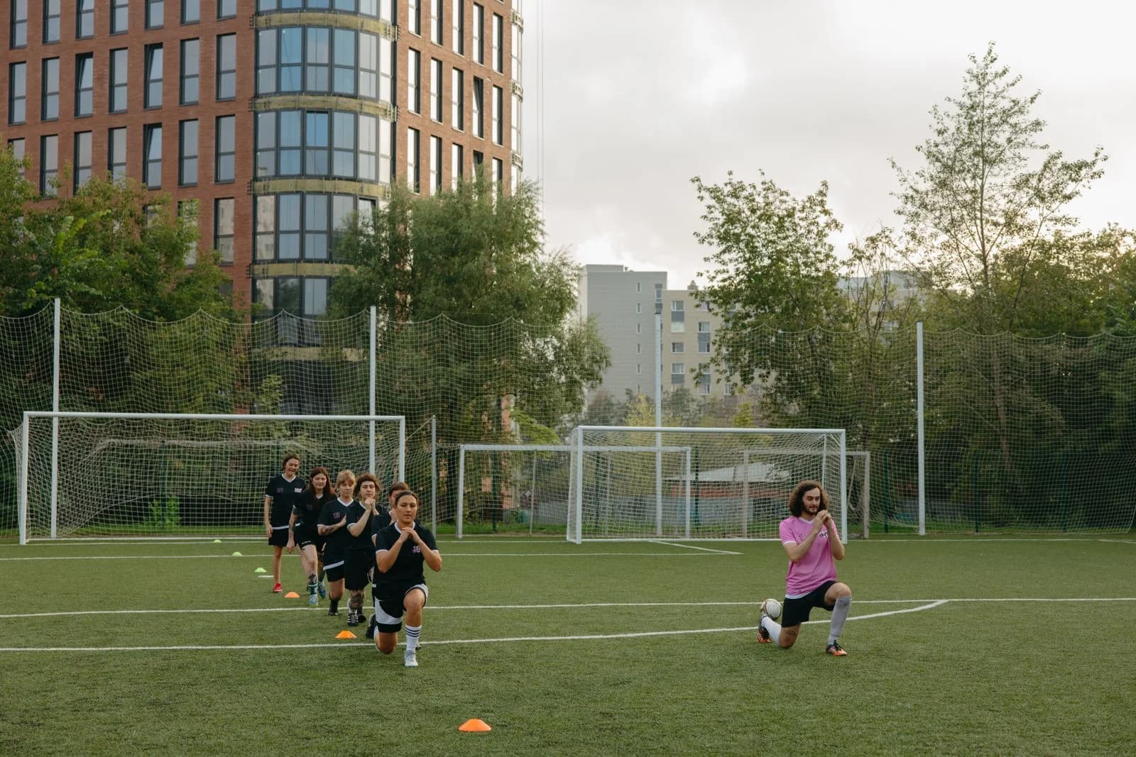 Young players warming up with a coach on a community football pitch