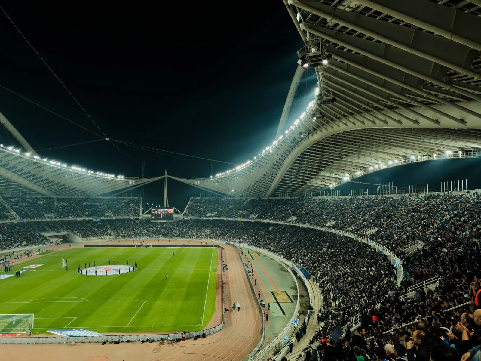 A football stadium filled with supporters under the evening floodlights