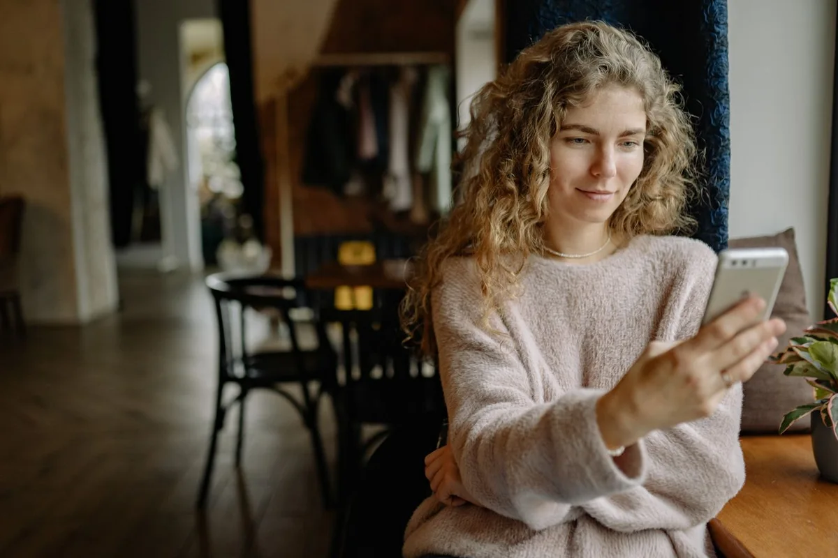 A customer checking her phone in a comfortable living room