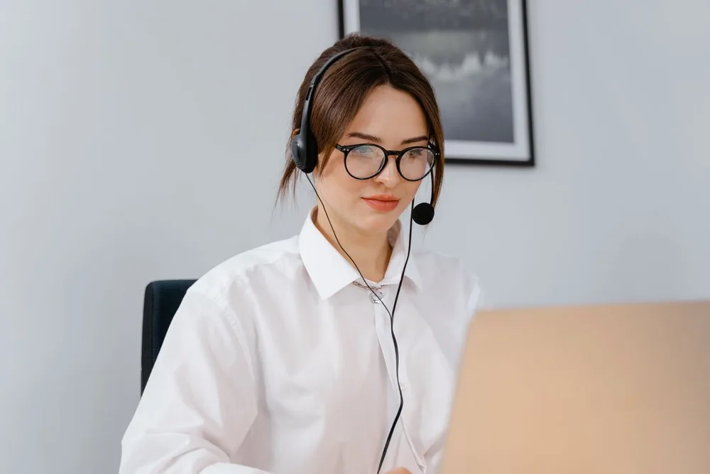 A support specialist wearing a headset at her laptop