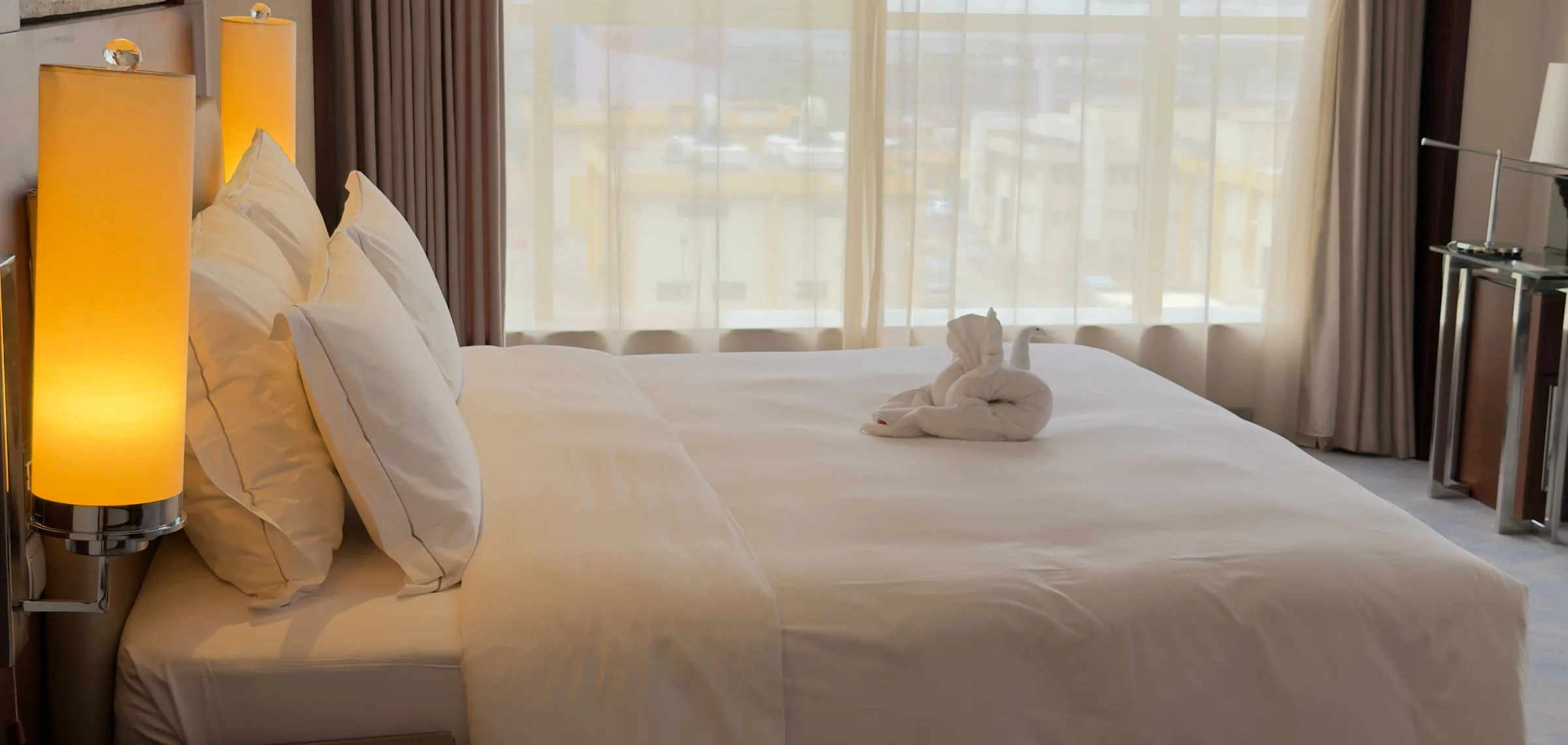 A hotel room with a large bed, bedside lamps, and a window