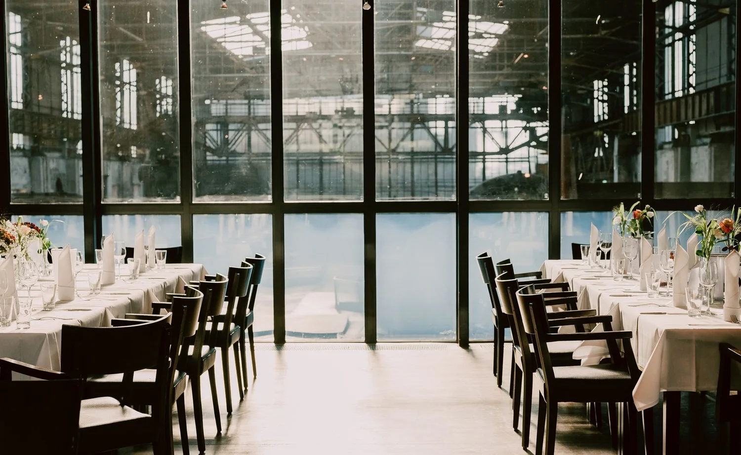 Sunlight falling across an elegant dining setup in a glass-walled event venue